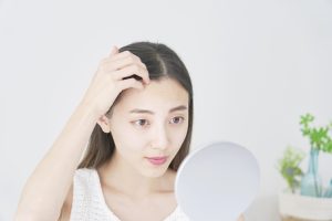 鏡で生え際を確認する女性